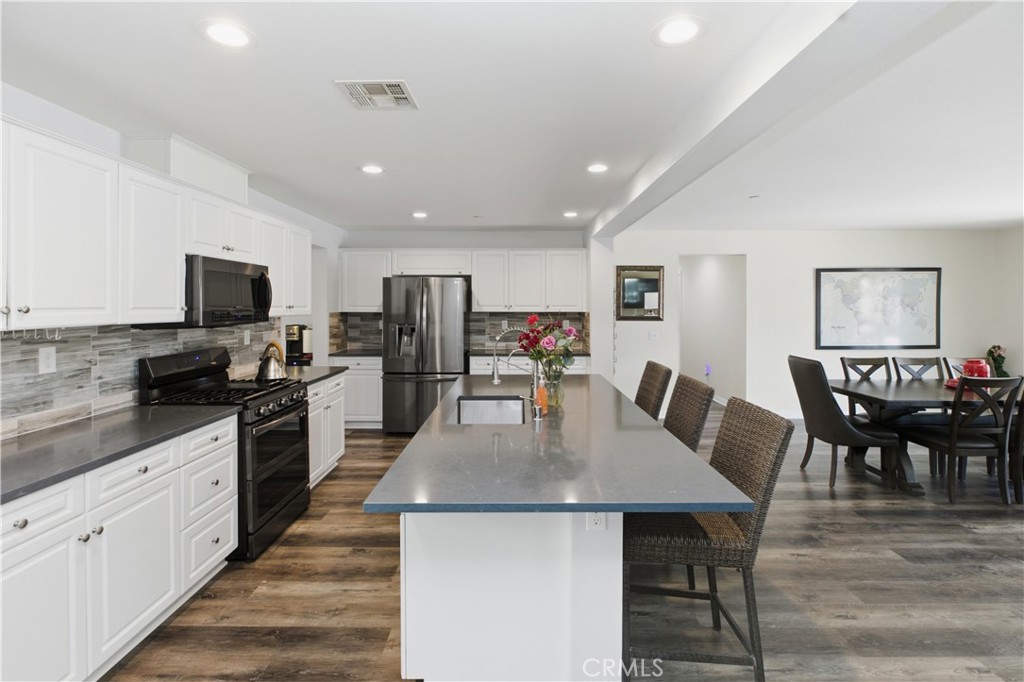 20583 Spring Street Riverside, CA 92507 - Photo 14 of 53 a kitchen with stainless steel appliances granite countertop a table chairs sink refrigerator and microwave