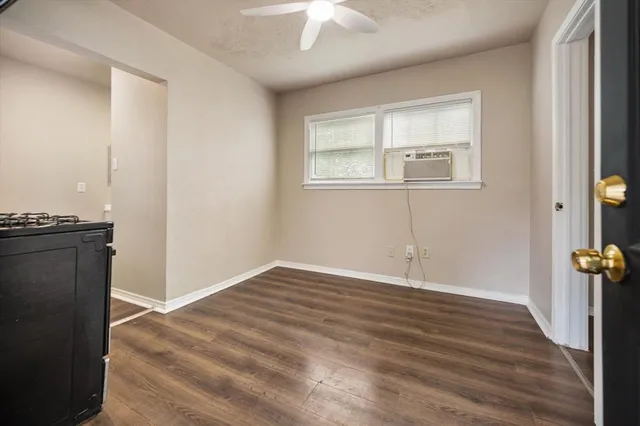 an empty room with wooden floor cabinet and windows