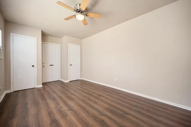 an empty room with wooden floor fan and windows