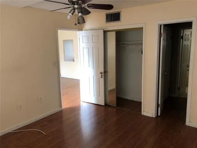 an empty room with wooden floor a ceiling fan and windows