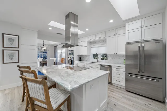 a kitchen with a refrigerator a stove a sink and white cabinets with wooden floor