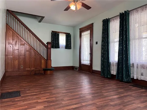 a view of empty room with wooden floor and fan
