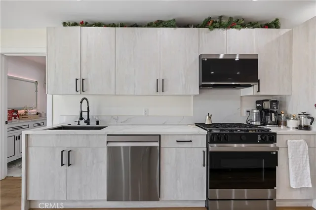 a kitchen with stainless steel appliances granite countertop a sink a stove a refrigerator a microwave and cabinets