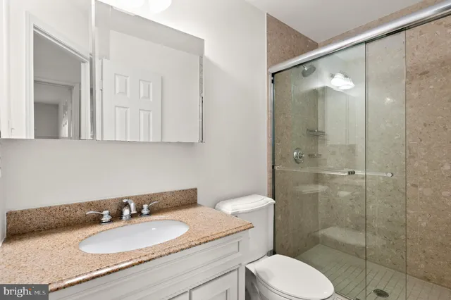 a bathroom with a granite countertop sink toilet a mirror and shower