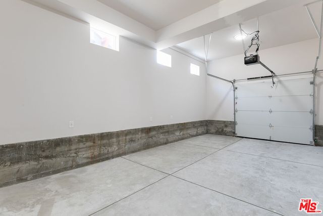 an empty room with chandelier fan and windows