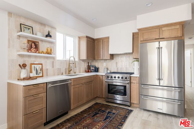 a kitchen with stainless steel appliances granite countertop a refrigerator sink and stove