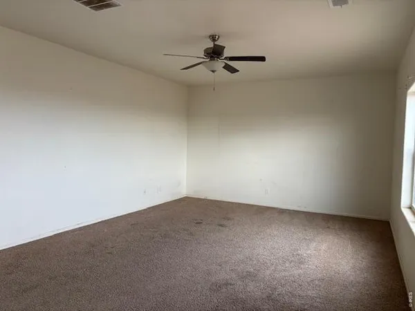 an empty room with a ceiling fan and window