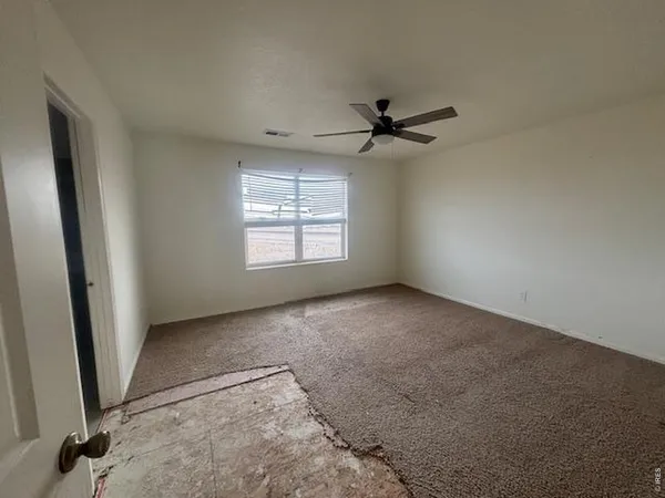 an empty room with windows and fan