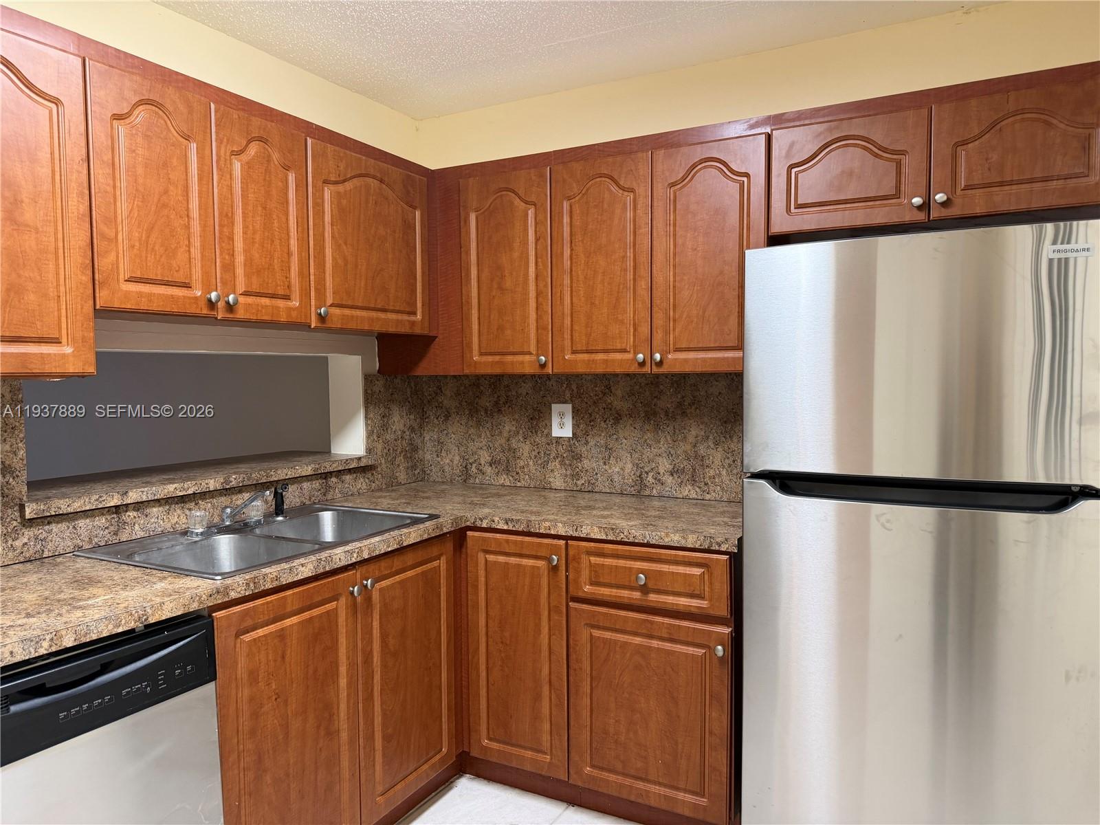 a kitchen with stainless steel appliances granite countertop a refrigerator a sink and dishwasher