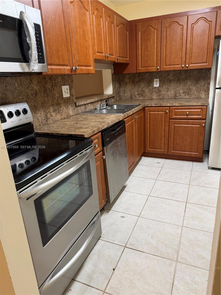 8500 Southwest 133rd Avenue Road, Unit 122 Miami, FL 33183 - Photo 19 of 22 a kitchen with stainless steel appliances granite countertop a stove a sink and a microwave