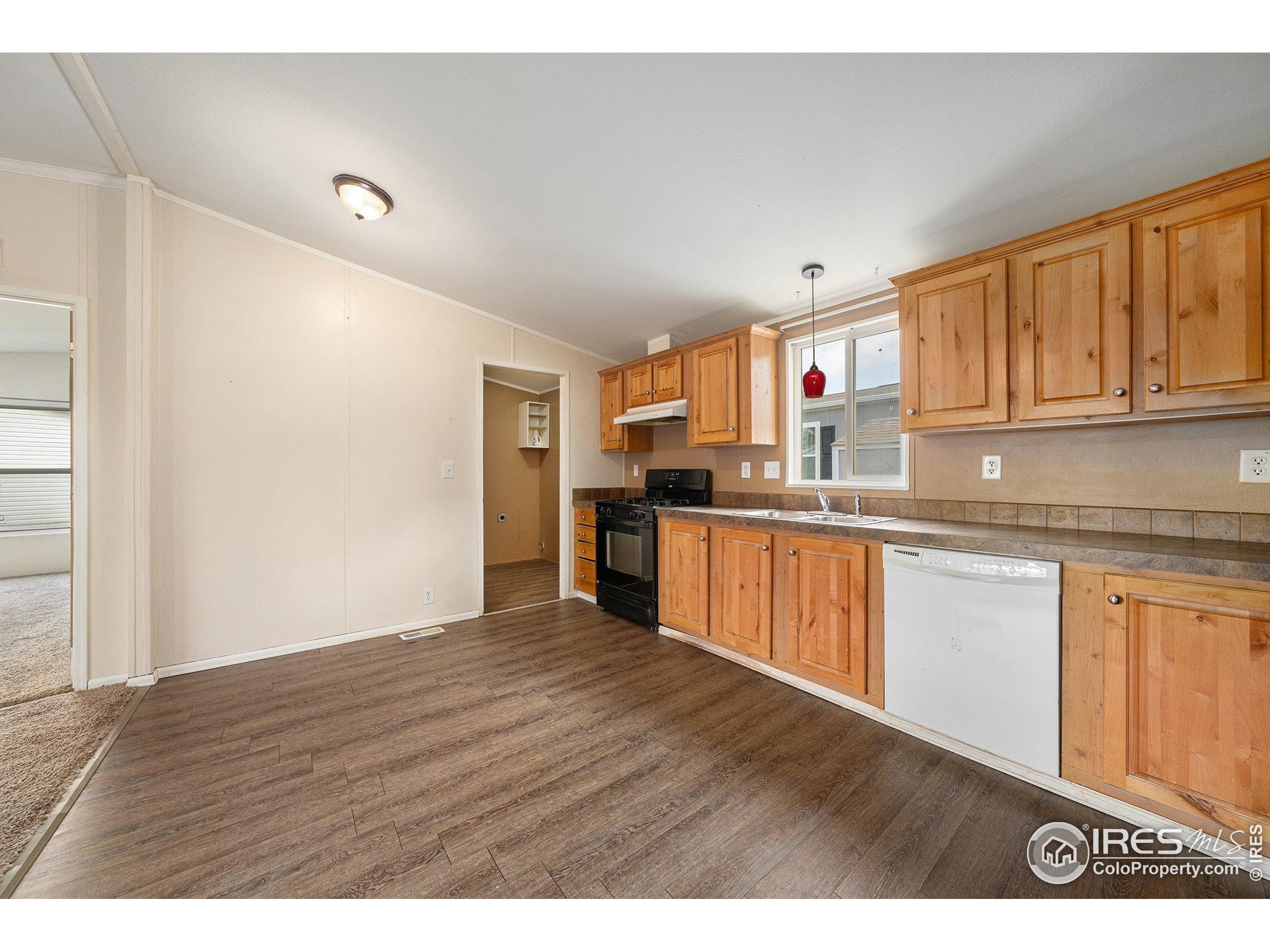 2500 East Harmony Road, Unit 191 Fort Collins, CO 80528 - Photo 6 of 22 a open kitchen with granite countertop a stove top oven a sink dishwasher and white cabinets with wooden floor
