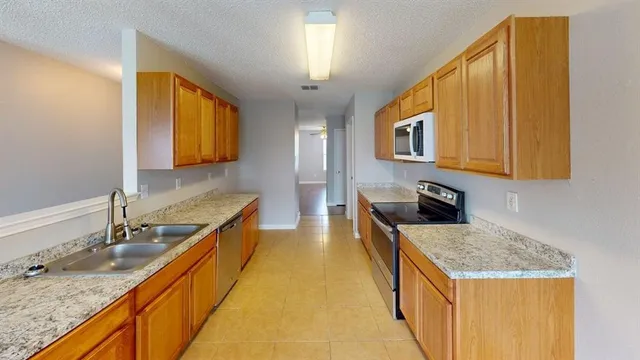a kitchen with stainless steel appliances granite countertop a sink a stove and a wooden cabinets