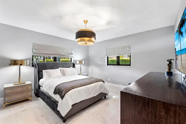 a bedroom with a bed a chandelier and a dresser