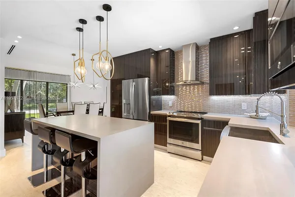a kitchen with stainless steel appliances a stove a sink a microwave a dining table and chairs