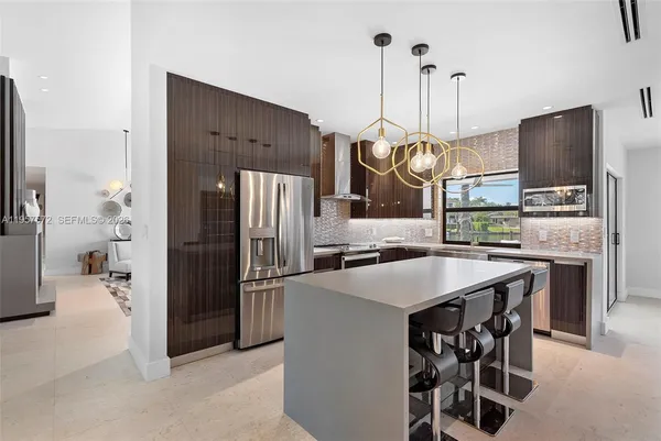 a kitchen with stainless steel appliances kitchen island granite countertop a refrigerator a stove and a sink with granite countertops