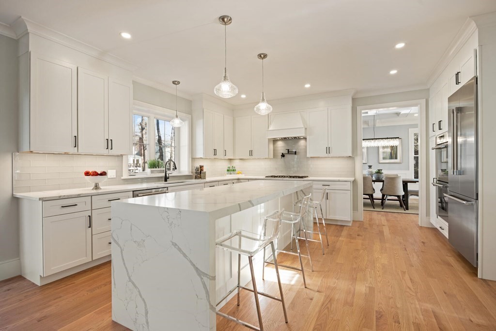 216 Concord Avenue Lexington, MA 02421 - Photo 2 of 7 a kitchen with stainless steel appliances kitchen island granite countertop a table chairs refrigerator and microwave