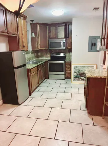 a kitchen with stainless steel appliances granite countertop a refrigerator and a stove top oven