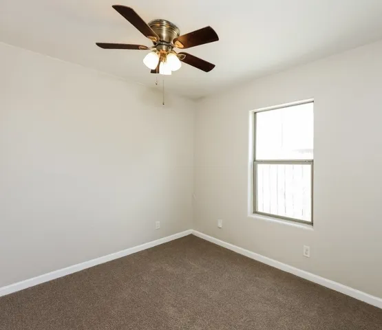 an empty room with a window and a fan