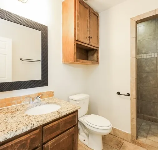 a bathroom with a granite countertop sink toilet and shower
