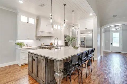 a kitchen with kitchen island a stove a table a sink and cabinets