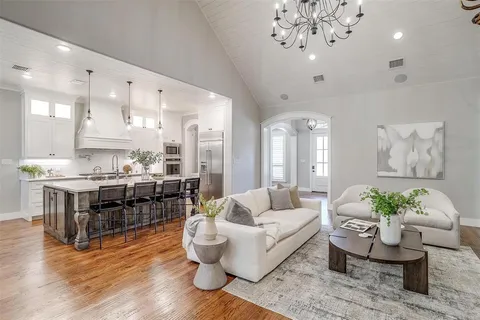 a living room with furniture kitchen view and a chandelier