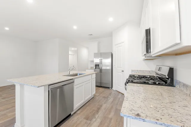 a kitchen with stainless steel appliances granite countertop a stove a sink and a refrigerator