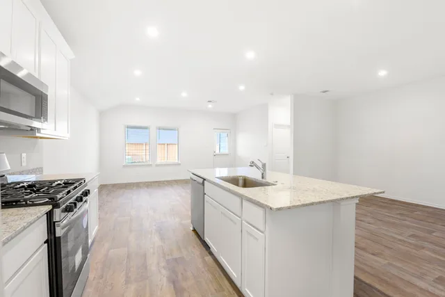 a view of kitchen with granite countertop cabinets and refrigerator