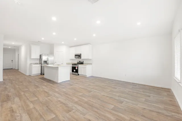 an empty room with wooden floor and windows