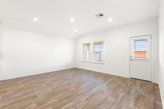 an empty room with wooden floor and windows