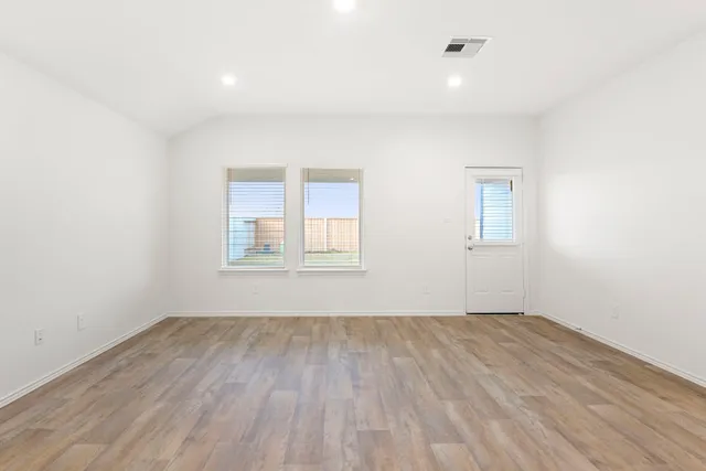 an empty room with wooden floor and windows