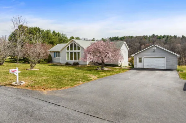 a view of a house with a big yard and large trees
