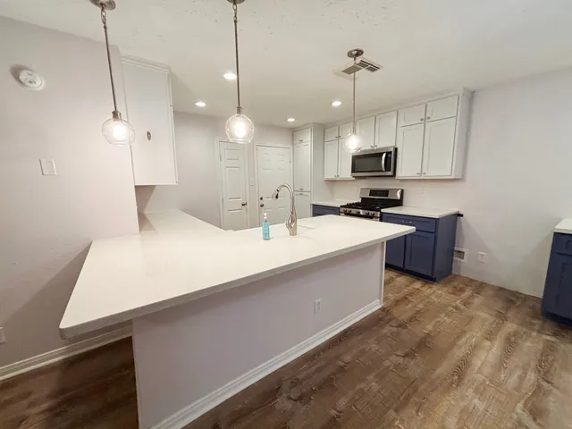 a large kitchen with kitchen island a sink a counter top space appliances and a window