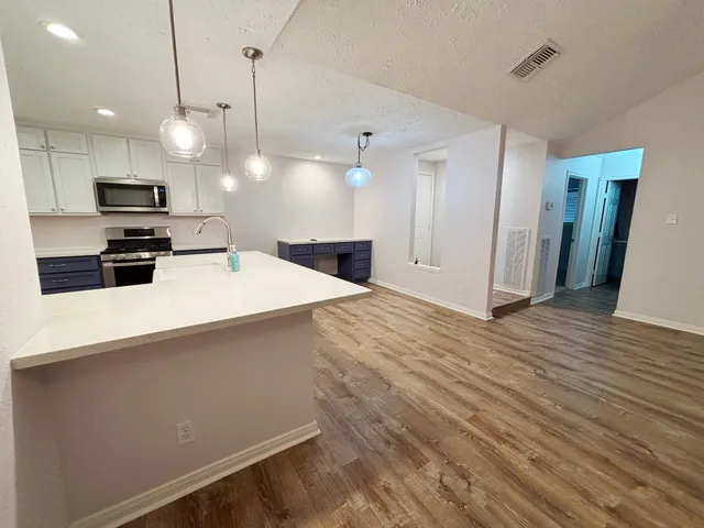 a large kitchen with kitchen island a stove a sink a refrigerator and a wooden floor