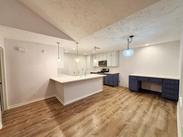 a large white kitchen with kitchen island a sink stainless steel appliances and cabinets