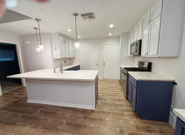 a large kitchen with kitchen island a sink a counter top space and cabinets