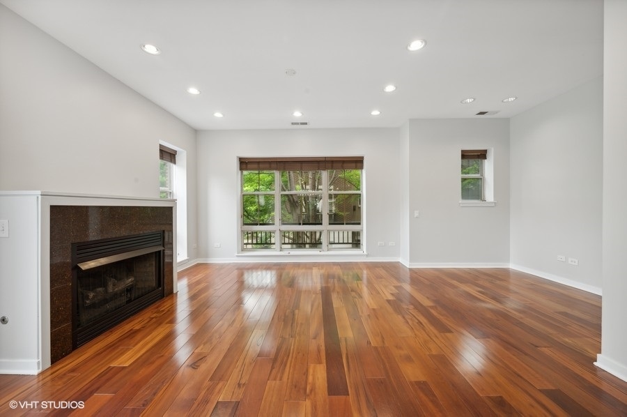 1231 West Arthington Street Chicago, IL 60607 - Photo 4 of 34 a view of an empty room with wooden floor fireplace and a window