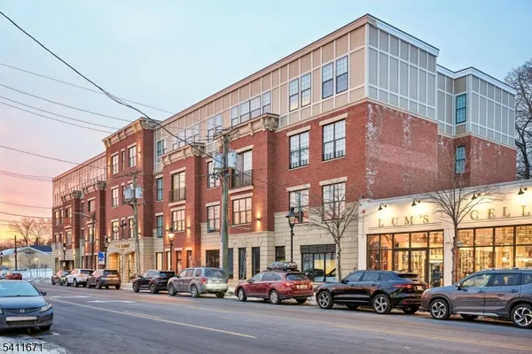 a city street lined with parked cars front of buildings