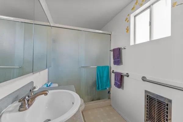 a bathroom with a sink a window and a shower