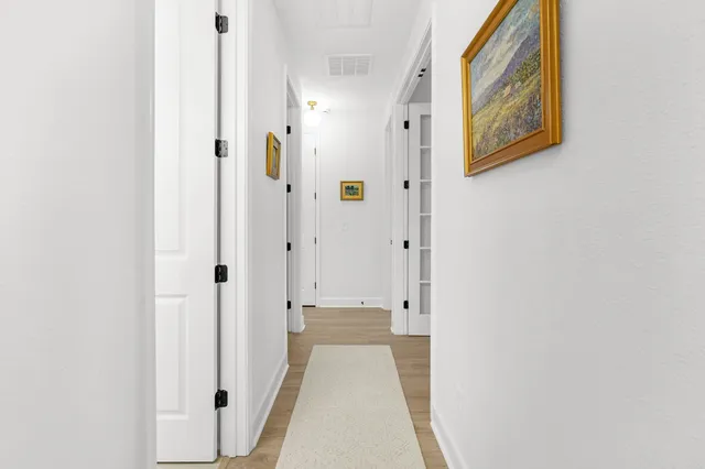 a view of a hallway with wooden floor and closet