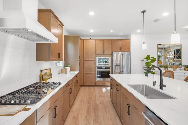 a large kitchen with stainless steel appliances a sink stove and cabinets
