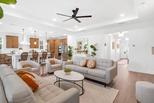 a living room with furniture kitchen view and a chandelier