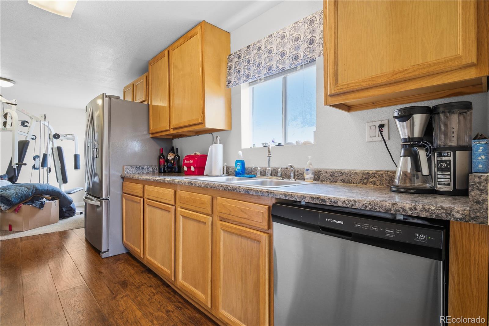 12205 Perry Street Broomfield, CO 80020 - Photo 5 of 22 a kitchen with granite countertop a sink stainless steel appliances a counter space and wooden floor