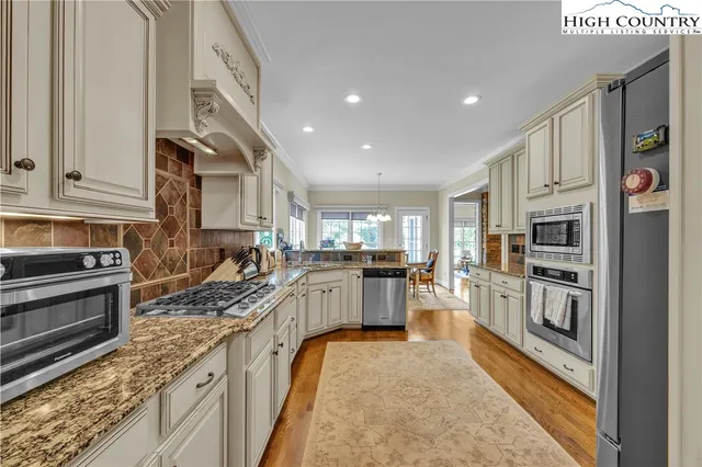 a kitchen with stainless steel appliances granite countertop a stove top oven a sink dishwasher a refrigerator and cabinets with wooden floor