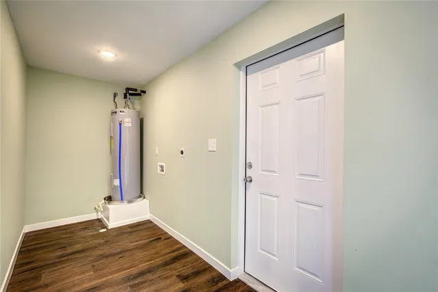 a view of an empty room with wooden floor and a bathroom