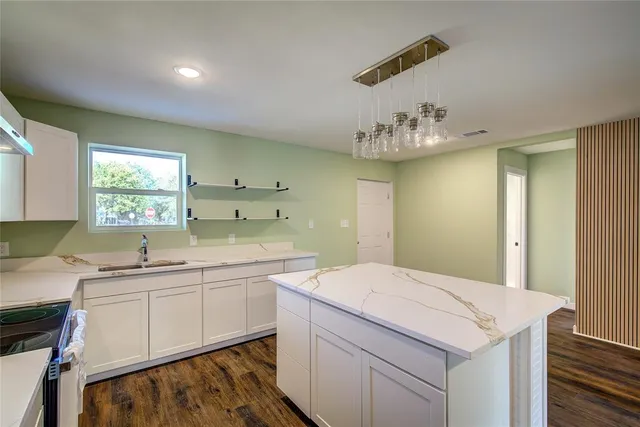 a room with a sink dishwasher and white cabinets with wooden floor
