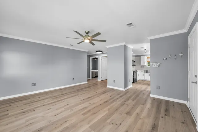 a view of a big room with wooden floor and a kitchen