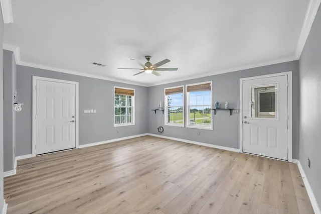 a view of an empty room with wooden floor and a window