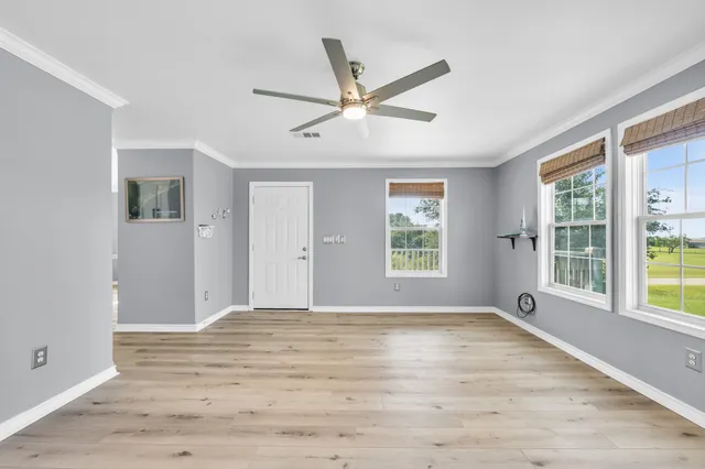 a view of an empty room with a window and wooden floor