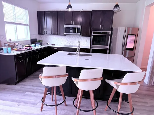 a kitchen with stainless steel appliances a dining table chairs and wooden cabinets
