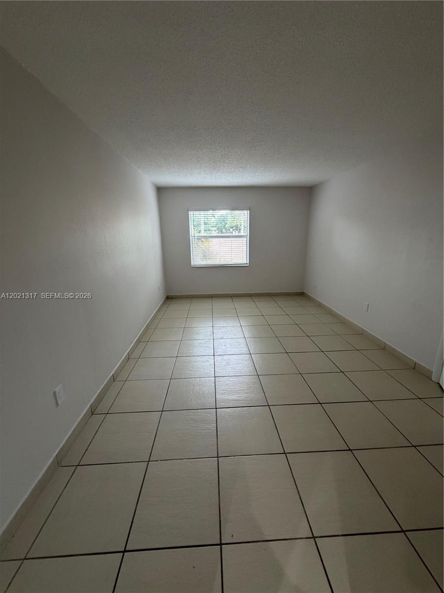 11201 Southwest 88th Street, Unit 102A Miami, FL 33173 - Photo 9 of 12 an empty room with tiles